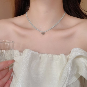 Close-up of a blue beaded necklace with a silver starfish pendant on a female neck