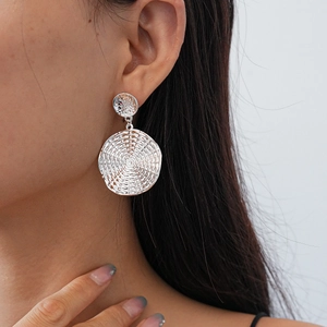 Close-up of silver geometric round earrings with woven texture on a model