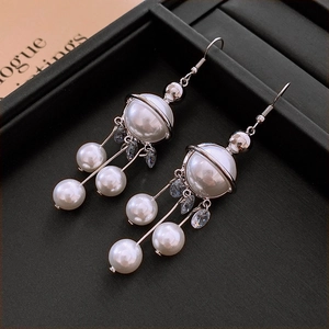 Vue détaillée des boucles d'oreilles planète en argent avec strass et franges de perles