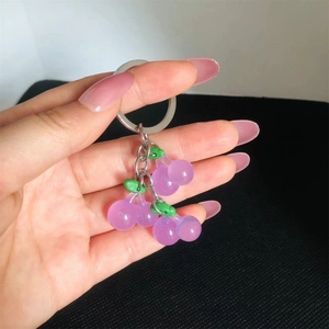 Close-up of a purple resin cherry keychain with a translucent finish and silver metal ring