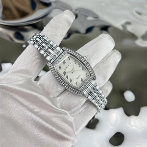 Close-up of a tonneau-shaped emerald-set quartz watch with sparkling rhinestones