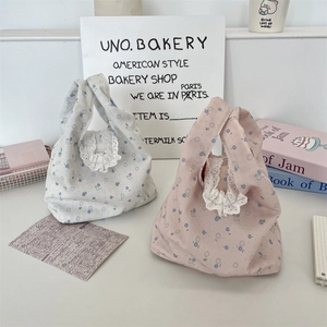 Dettaglio di borse tote in tela floreale con raffinati bordi in pizzo bianco sui manici