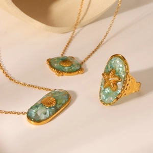 Close-up of ocean-style gold starfish necklace and ring set with green abalone shell