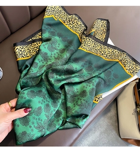 Détail d'un foulard en soie vert à fleurs avec bordure léopard sur un canapé