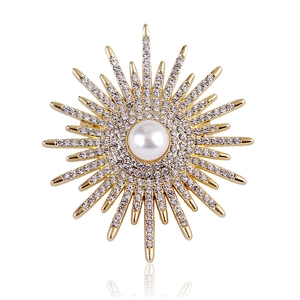 Detailed macro of a sunburst brooch with a central pearl and sparkling rhinestones