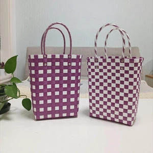 Detail view of purple and white woven tote bag with plastic checkerboard pattern and handles