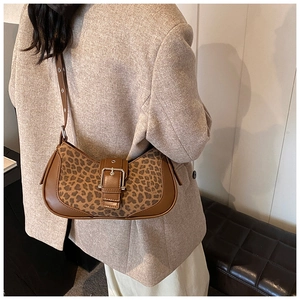 Détail du sac à main léopard avec liseré en cuir marron et boucle en métal sur veste
