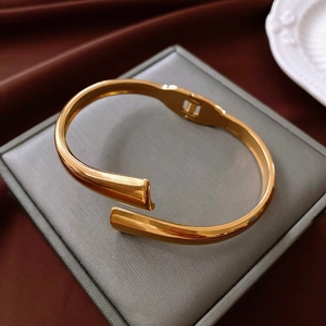 Detail of gold teardrop wrap bracelet with spring hinge on luxury velvet background