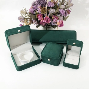 Macro shot of dark green velvet jewelry box set with white lining and pearl button details