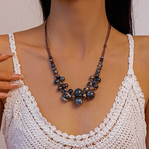 Détail du collier ras du cou tissé avec perles en céramique bleues et marron style boho