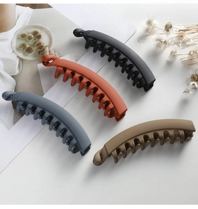 Matte large banana hair clips in black, orange, blue, and khaki displayed on white surface