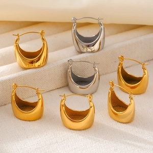 U-shaped thick metal hoop earrings in gold and silver finishes on textured fabric