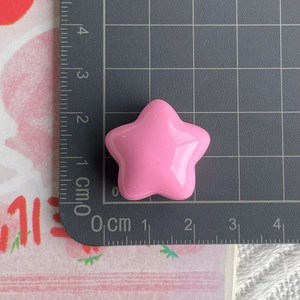 Detailed scale view of a 2.5cm chunky pink resin star bead on a gray measuring mat