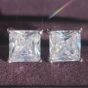 Macro shot of square-cut white zircon stud earrings in silver four-prong setting