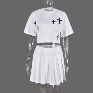 Dettaglio della stampa croce gotica su t-shirt corta bianca e gonna a pieghe