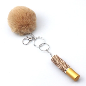 Brown faux fur pompom keychain with a gold rhinestone-encrusted perfume spray bottle