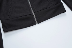 Detalle de la cremallera metálica plateada y el dobladillo acanalado en sudadera negra