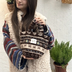 Detail of bohemian plush handbag showing texture, floral pattern, and woven brand label