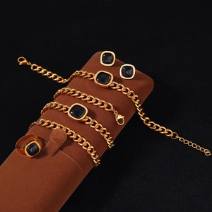 Parure de bijoux dorés avec chaîne cubaine et opale noire carrée sur un présentoir brun