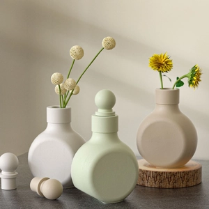 Three minimalist ceramic vases in matte white, mint green, and beige with round stoppers