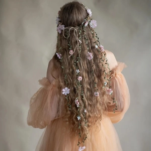 Bohemian floral crown with pink flowers and green vines on a model in an orange dress