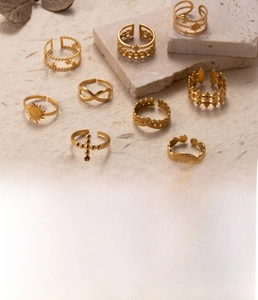 Detailed flat lay of gold titanium steel rings featuring sun and cross motifs