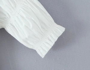 Détail du poignet bouffant blanc avec élastique froncé sur une robe à manches