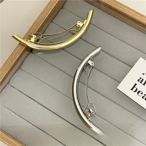 Close-up of elegant curved gold and silver metal hair clips on a velvet tray