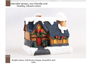 Close-up of resin Christmas house with glowing lights and snowy roof detail