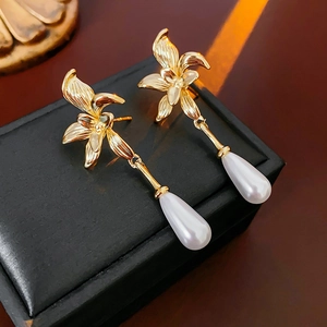 Detailed close-up of 14K gold plated flower stud earrings with pearl water drop charms
