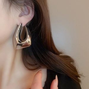 Gros plan de grandes boucles d'oreilles géométriques irrégulières argentées sur modèle