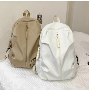Detail view of large beige and white minimalist backpacks on a white textured background