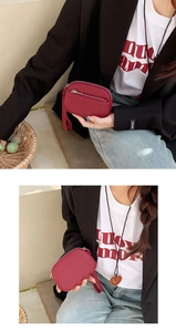 Close-up of a small red leather coin purse with wrist strap held by a model