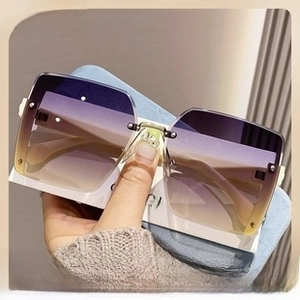 Close-up of rimless butterfly sunglasses with gradient purple lenses and gold metal temples