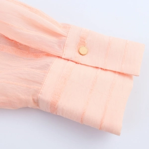 Pink striped blouse cuff detail with gold button and breathable fabric texture