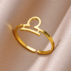 Macro shot of gold Libra zodiac symbol adjustable ring on elegant champagne satin fabric