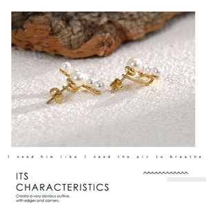 Close-up of elegant gold base earrings with multiple white pearls on white sand backdrop