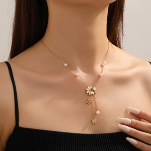 Dettaglio della collana dorata con ciondoli a forma di ape e fiori e perle indossata