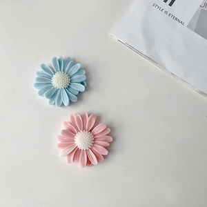 Close-up of DIY daisy flower resin charms in sky blue and soft pink with petal details