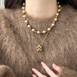 Detail of double-layer necklace with tiger eye stone pendant and beaded pearl strand