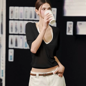 Street style shot of a black sheer long-sleeve top with white halter neck underlay