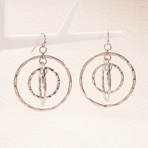 Detailed view of layered silver geometric circular earrings on a white display stand