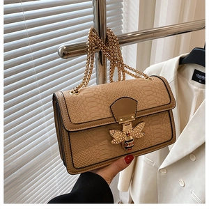 Detailed close-up of khaki snakeskin textured leather with a golden bee jewel clasp