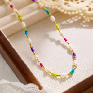 Detail of bohemian colorful seed beads and white irregular pearls on gold plated necklace