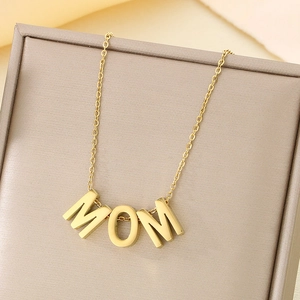 Close-up of golden MOM heart pendant necklace displayed in a beige jewelry gift box