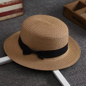 Detailed flat lay of a flat top straw hat with a black ribbon bow on a textured background