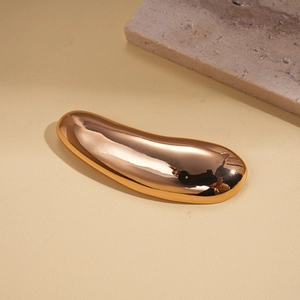 Detail view of the metallic teardrop brooch with a polished gold finish on leather