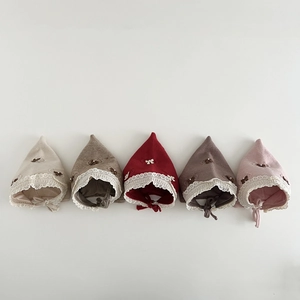 Detail of five knit baby elf hats with delicate lace trim and adjustable chin straps