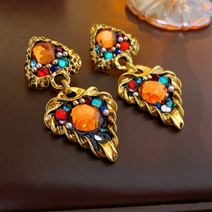 Close-up of vintage baroque triangle earrings with orange gemstones and gold finish