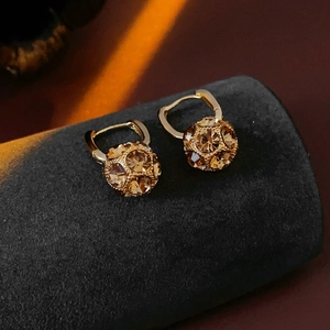 Detail of gold plated sphere earrings with champagne rhinestones on a velvet stand